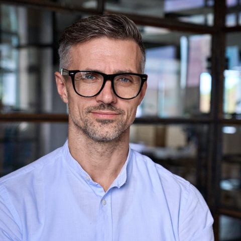 Mature businessman leader manager in office, headshot business portrait. IT specialist kijkt recht in de camera